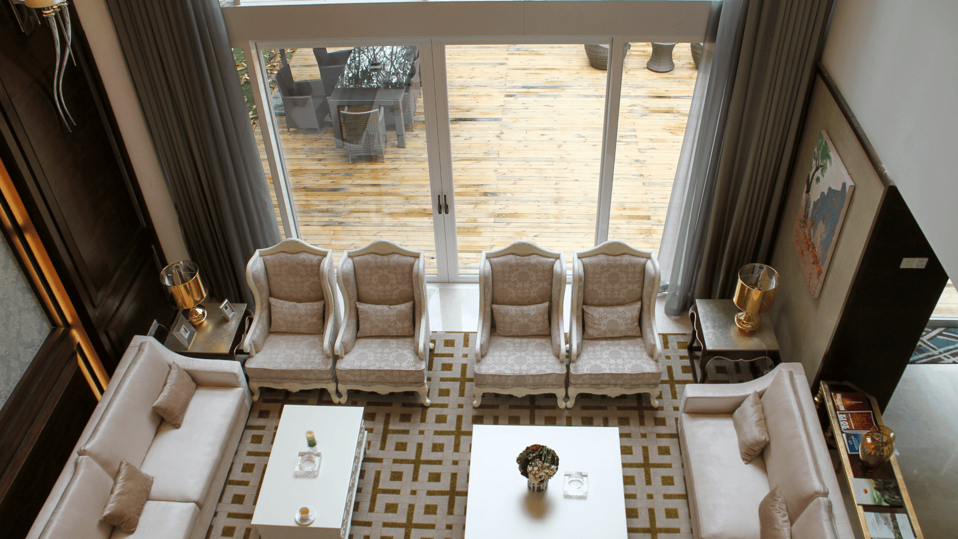 High-angle view of a luxury living room connecting seamlessly to an outdoor wooden deck through wide-open LIKI lift and slide doors, creating a unified entertaining space.