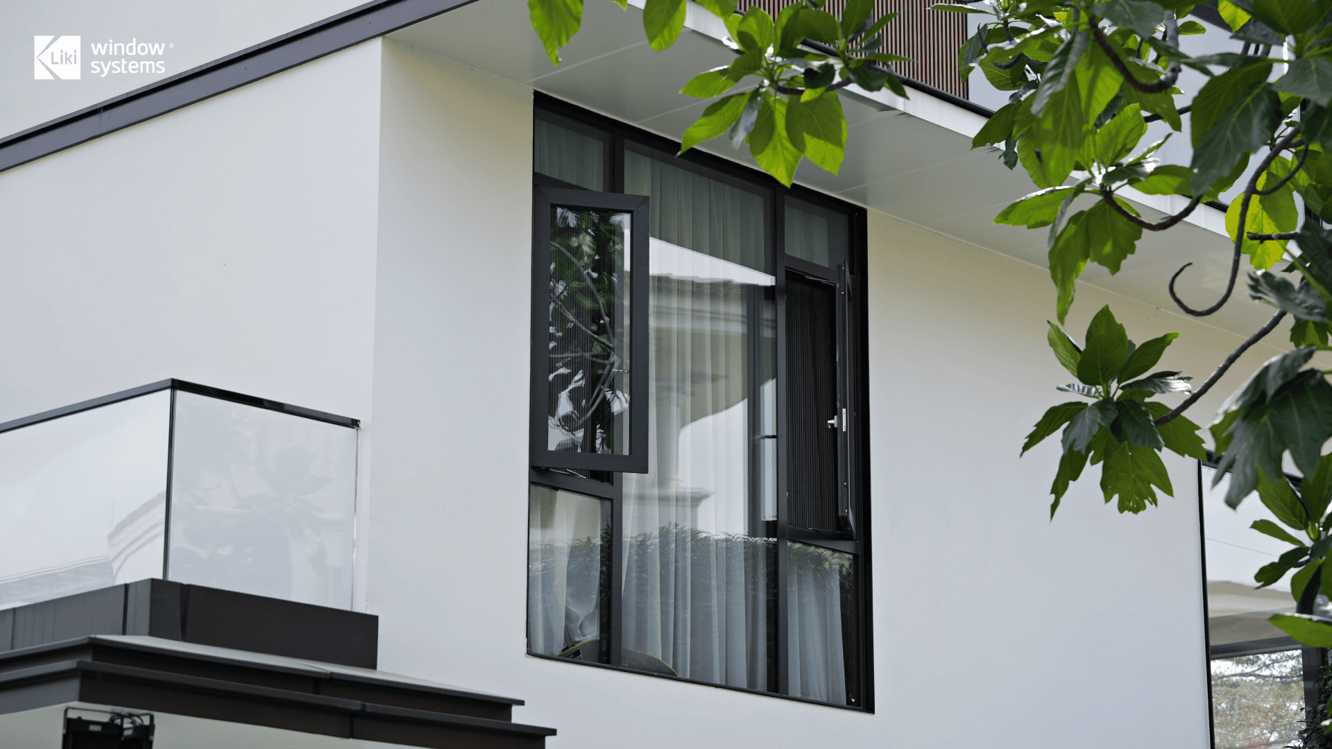 LIKI high-performance aluminum casement window featuring a slim black frame and integrated insect screen, fully opened to maximize airflow on a modern luxury home.