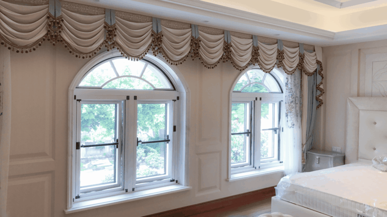 Custom-engineered arched windows by LIKI in a traditional luxury bedroom, featuring ornate valances and high-performance security integrated casement systems.