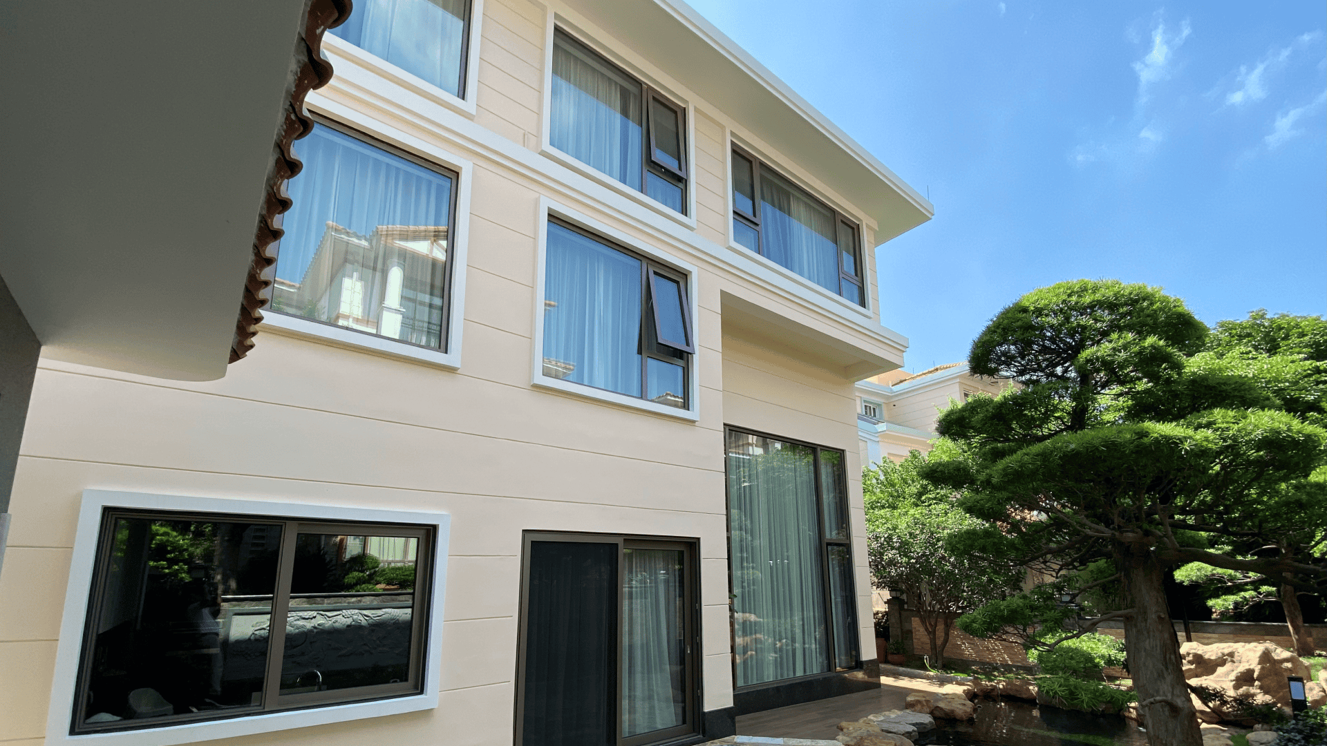 Exterior view of a custom three-story villa featuring Liki Systems' 73 Series concealed-frame parallel opening windows on the ground floor and 100-95 Series awning windows on upper levels.